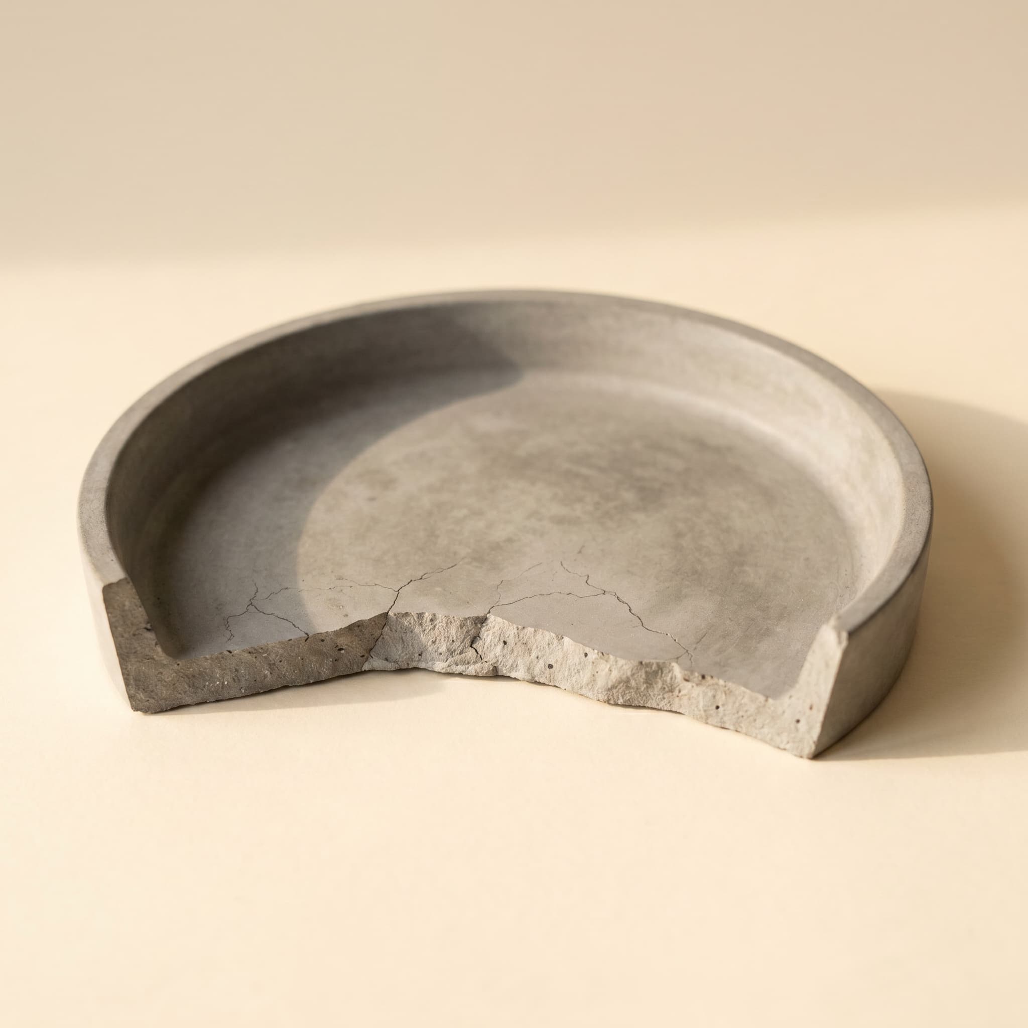 Grey round saucer with sculptural wedge bite missing