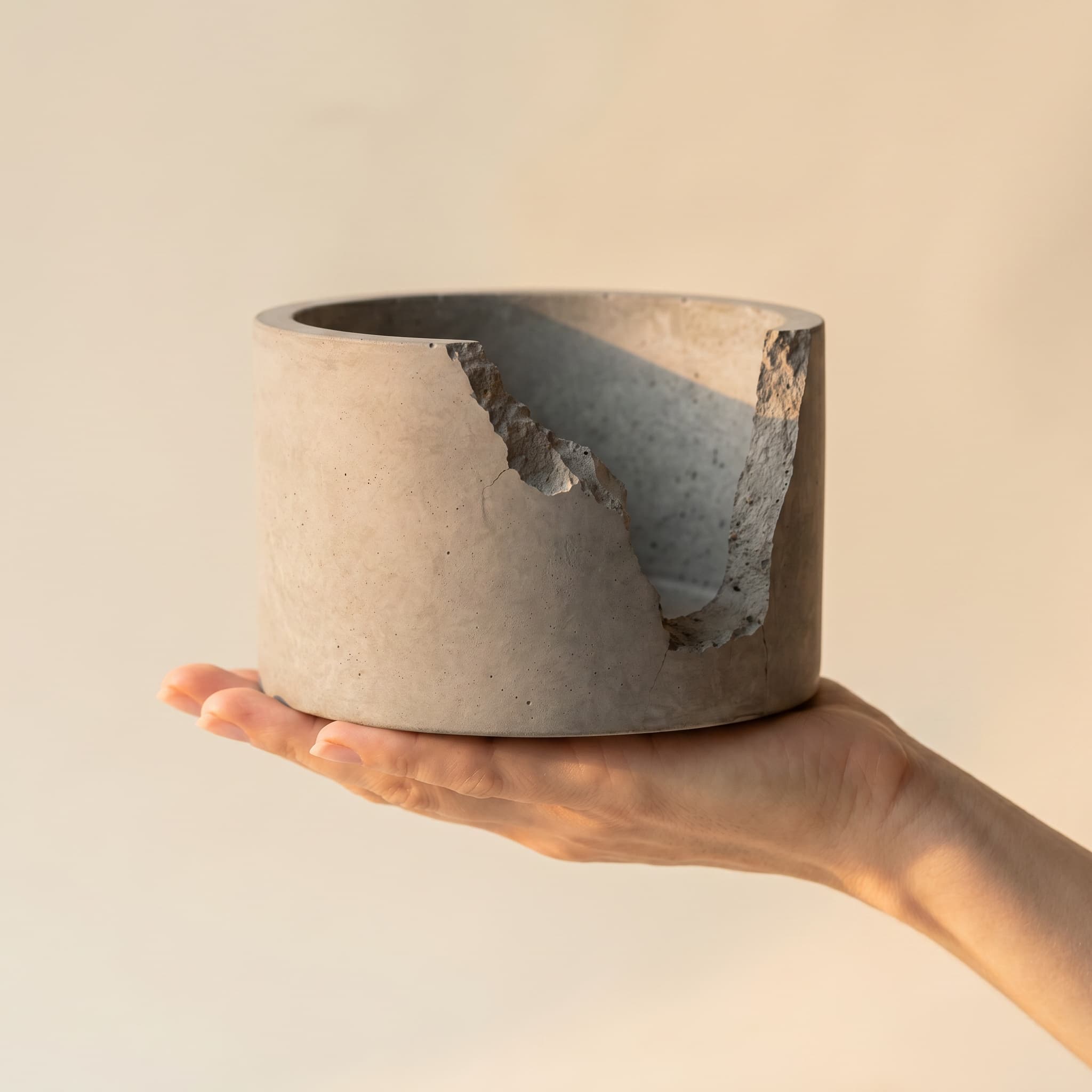 Broken wide grey vessel held in a hand
