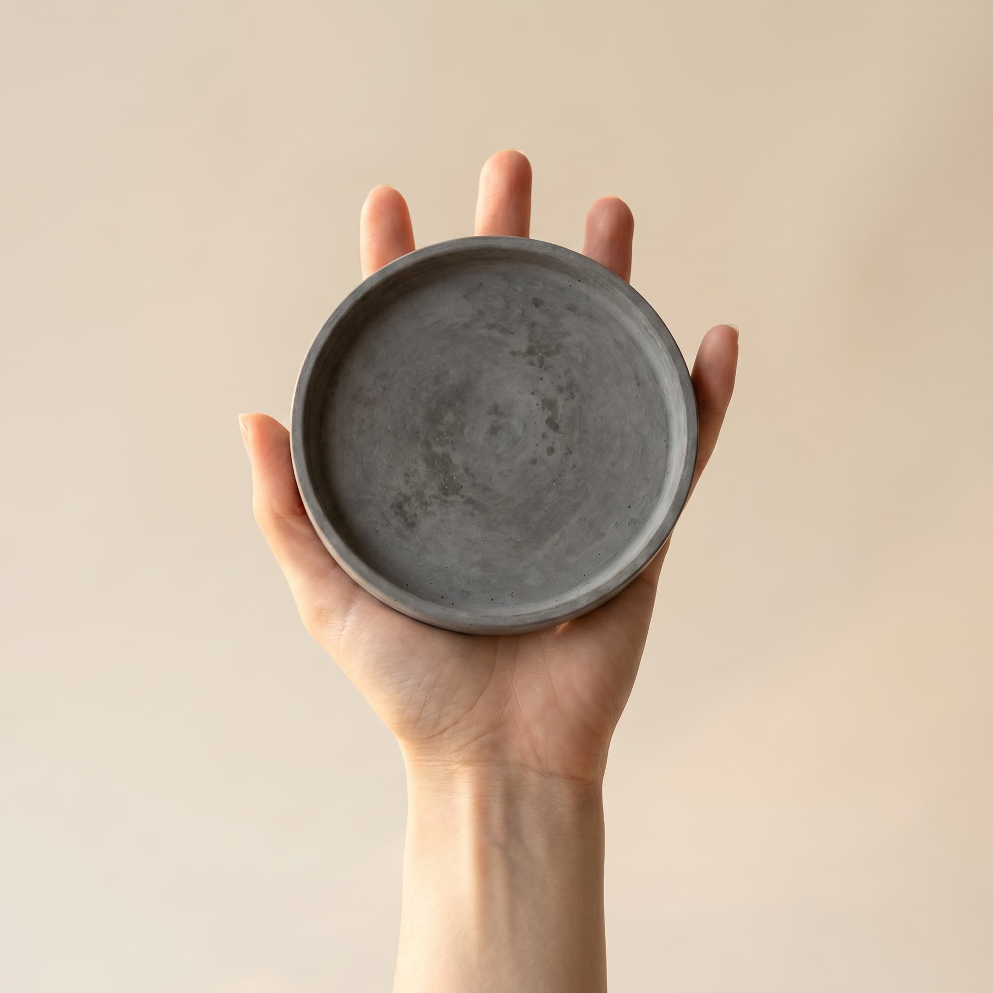 Round grey saucer held in a hand