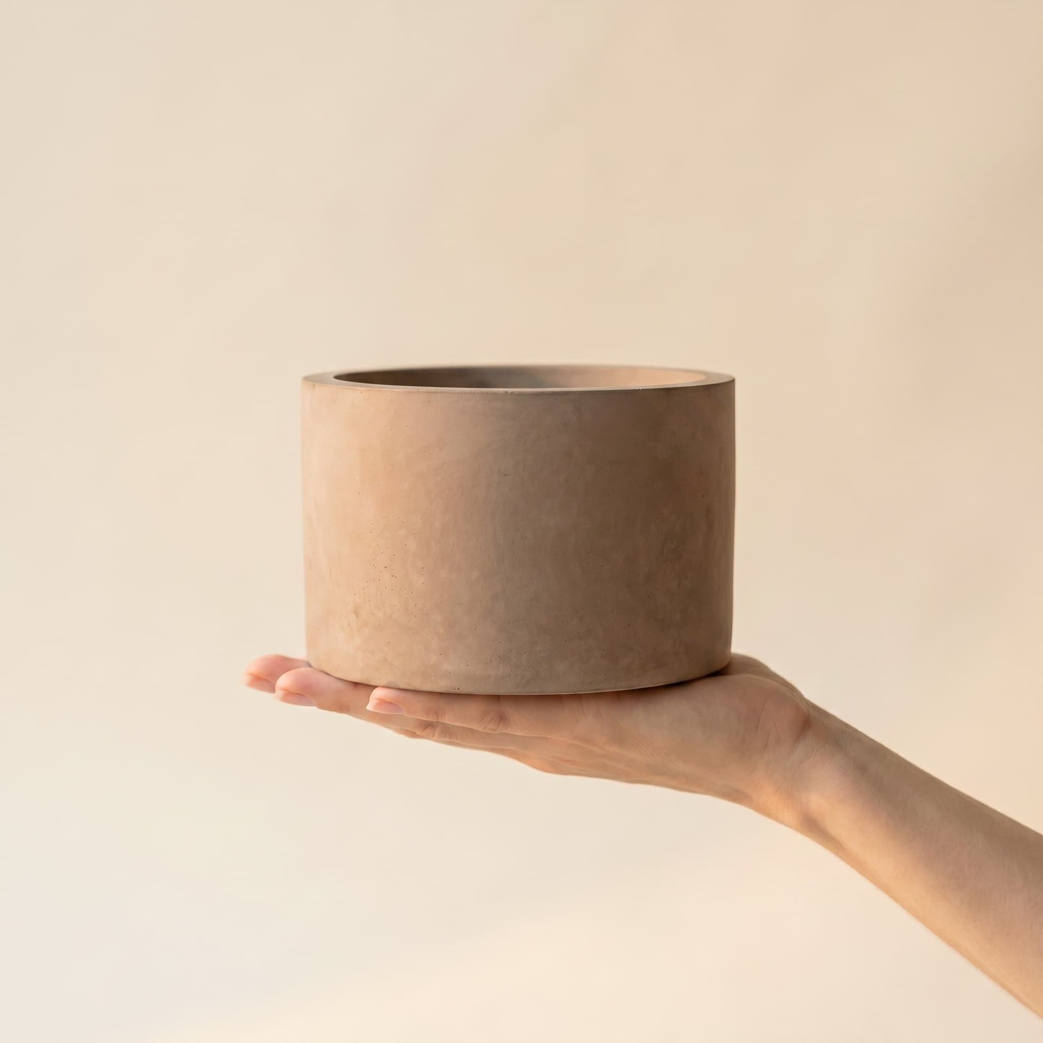Wide taupe cylinder held in a hand