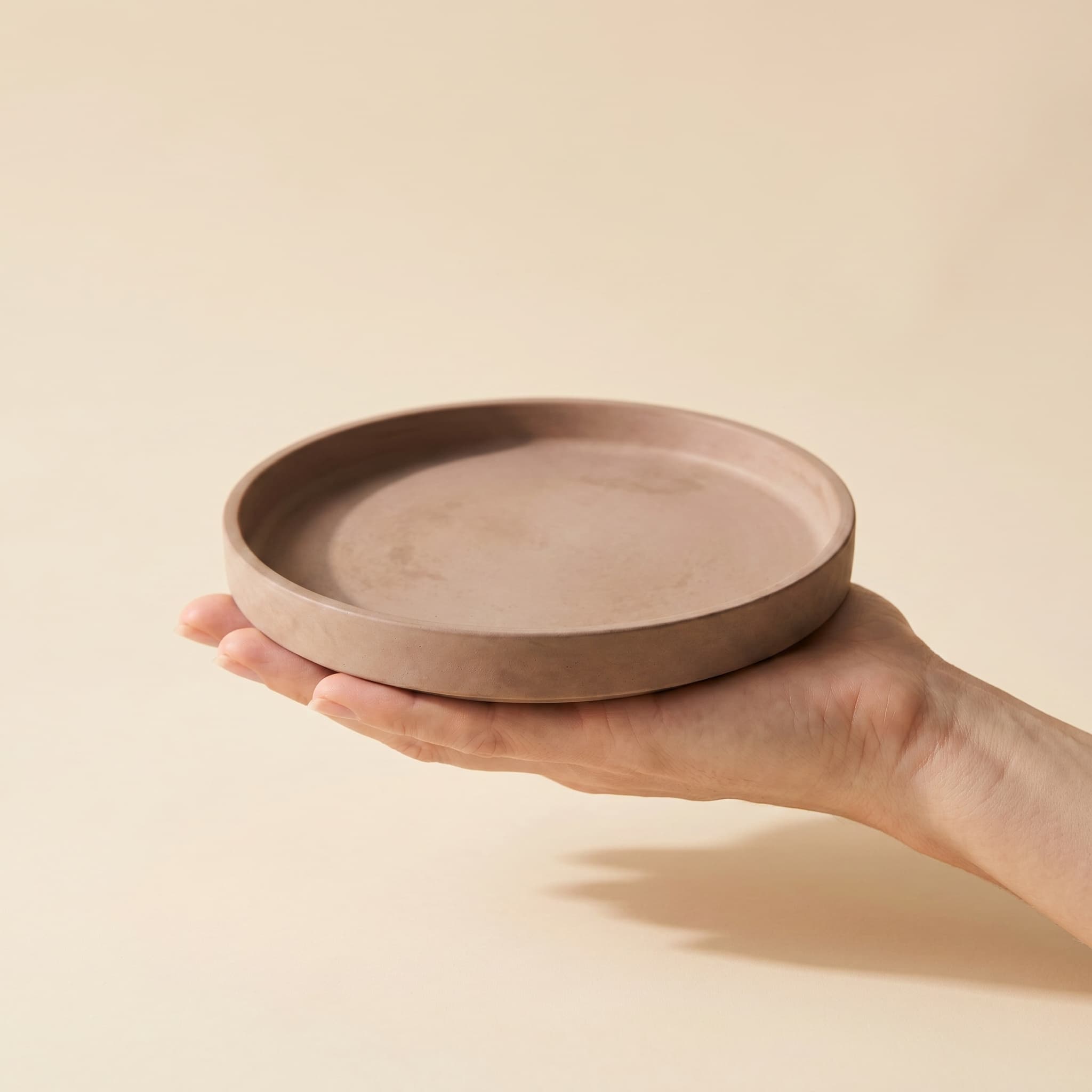 Round taupe saucer held in a hand