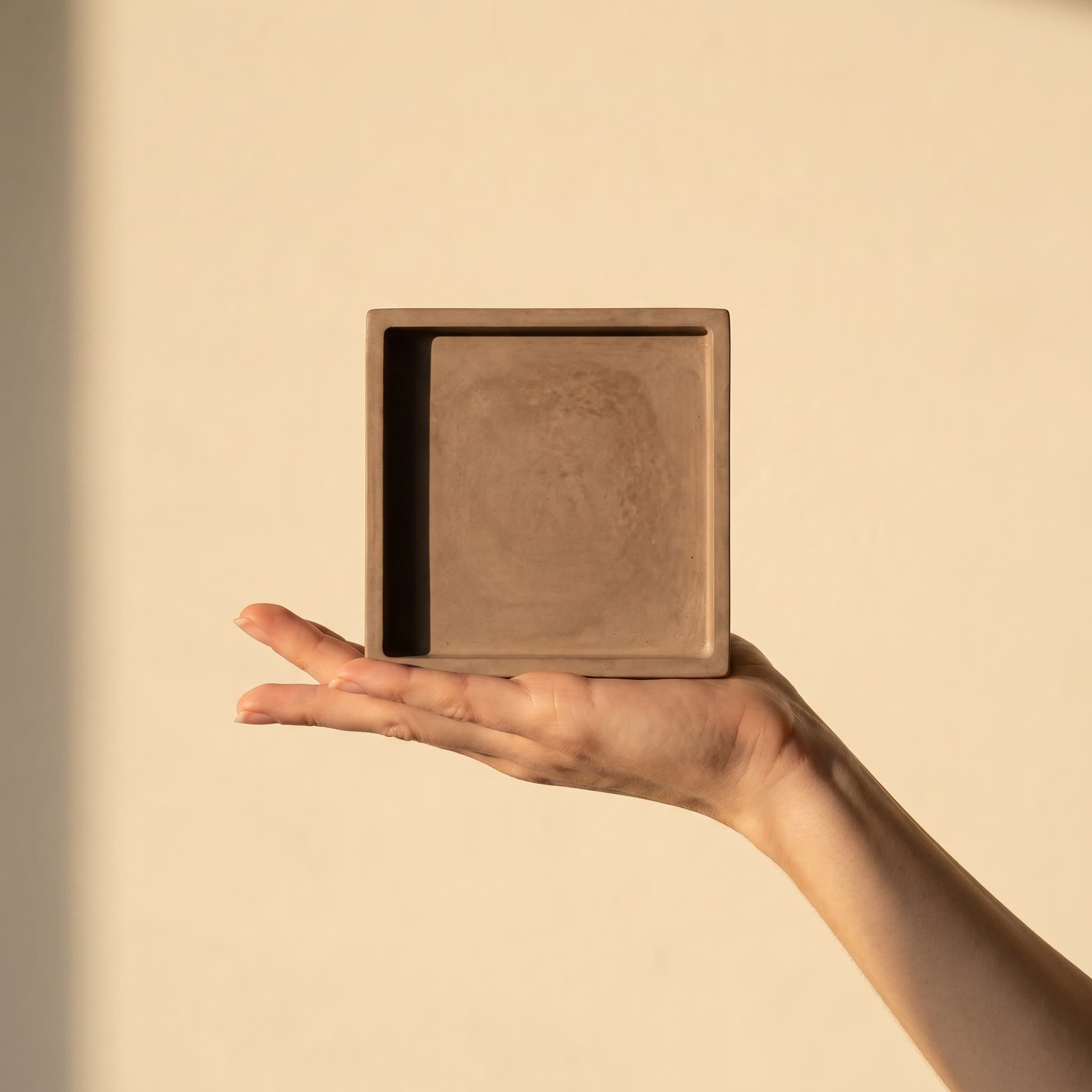 Square taupe saucer held in a hand